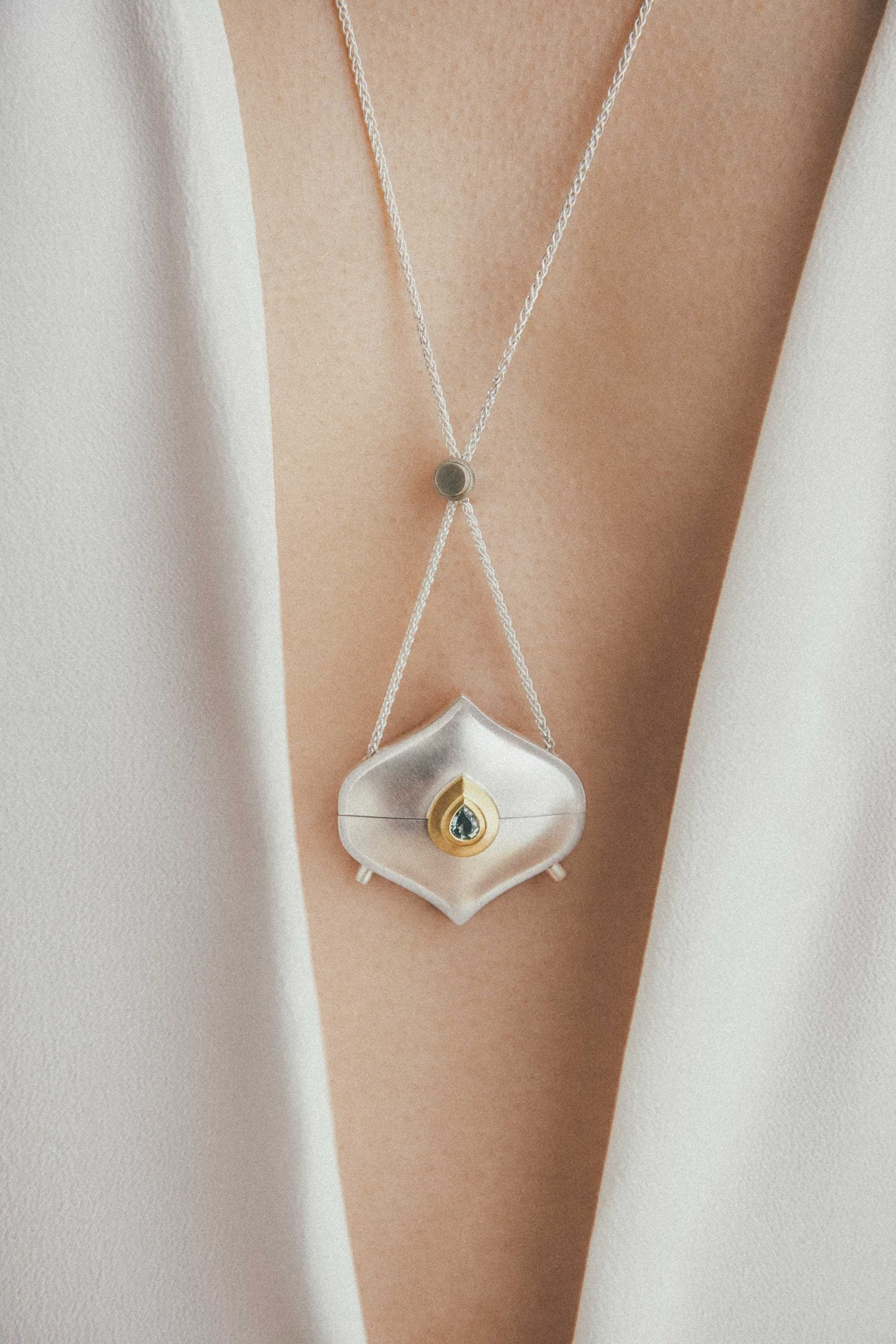 Moznabi's Alborz Locket made with silver, gold and a green sapphire