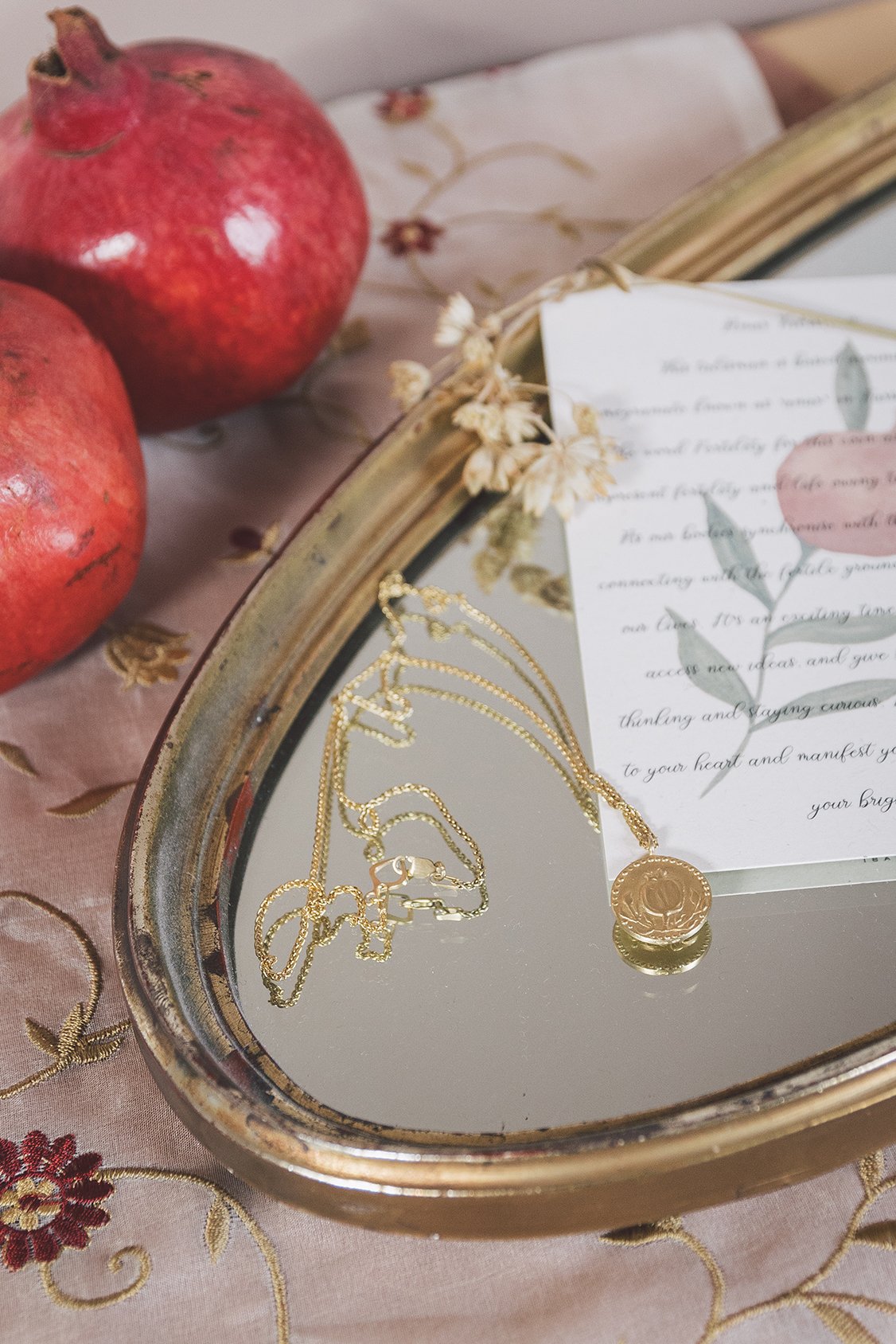 Anar Gold Pendant and chain on a silver tray. 