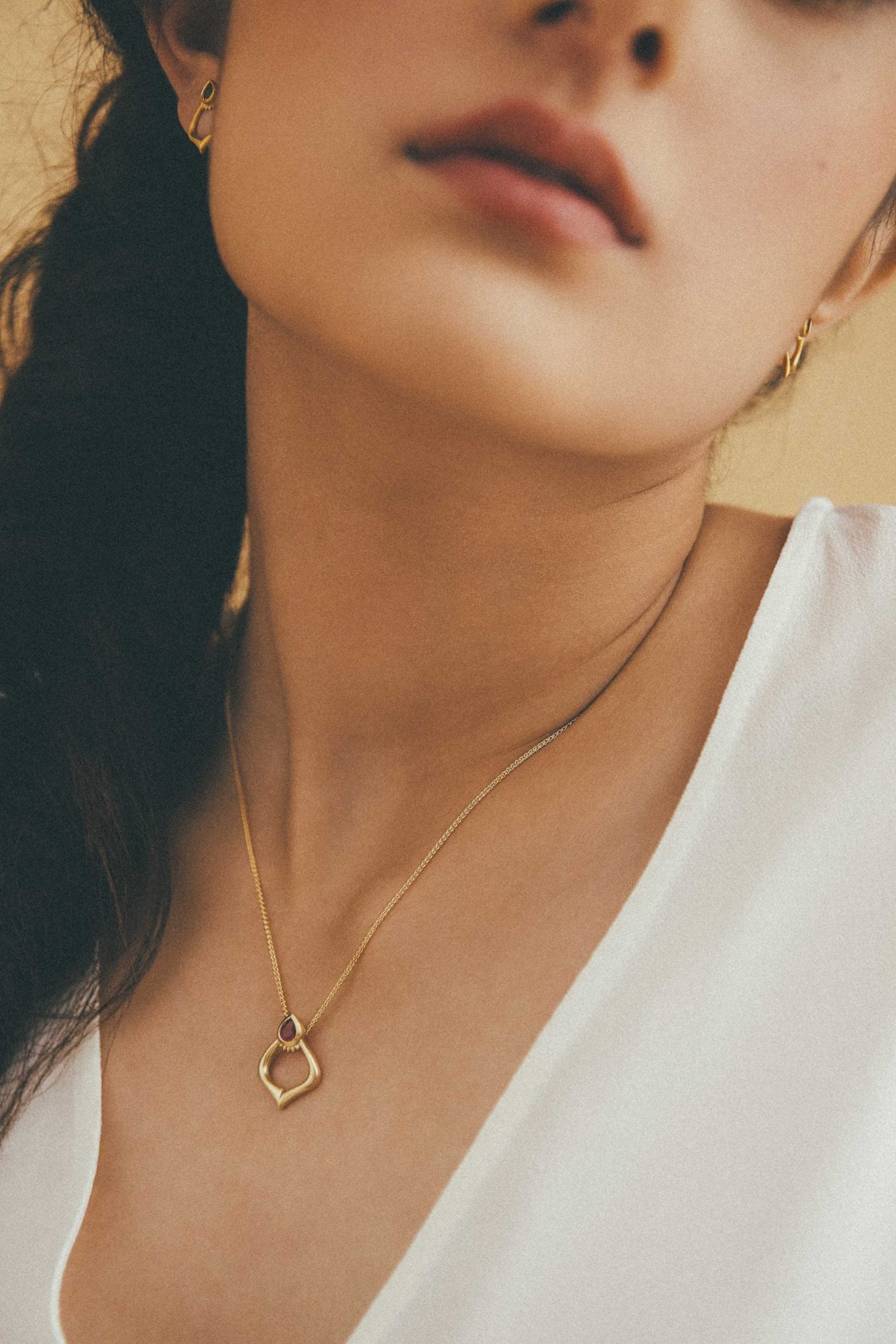 Woman wearing the Alborz Pendant made with Gold and a ruby gem stone